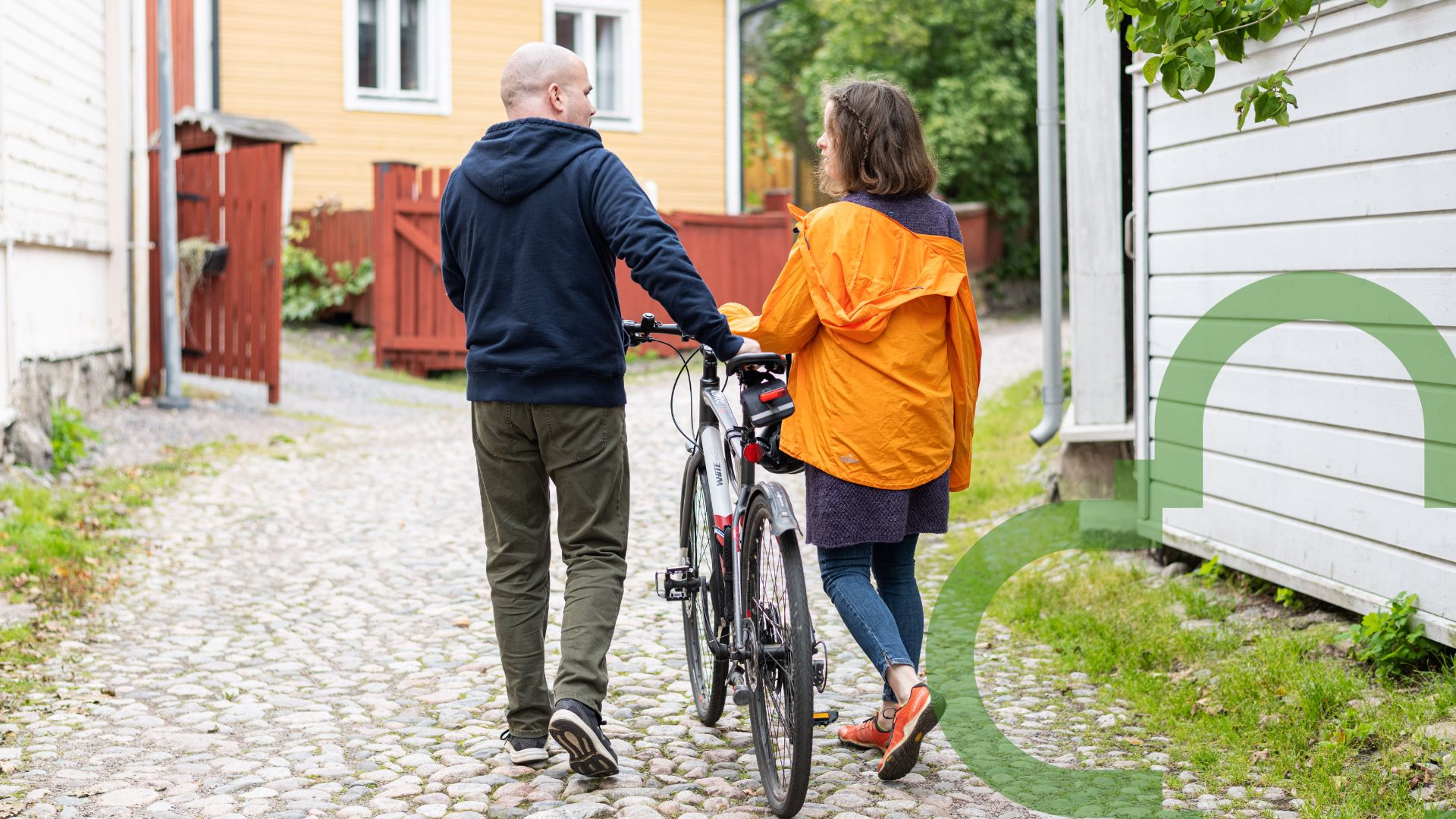 Pariskunta kävelee vanhassa kaupungissa, polkupyörä mukana.