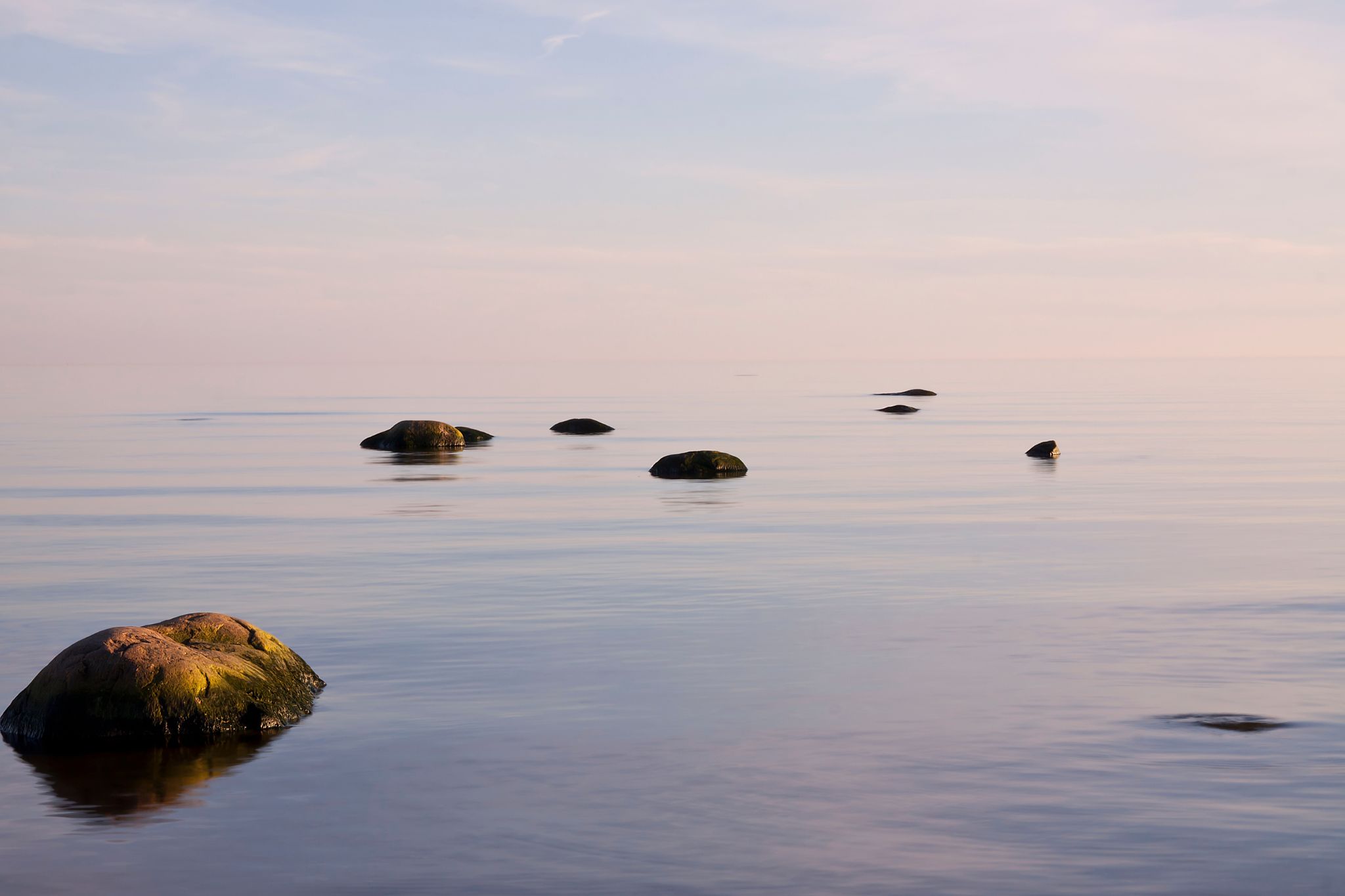 Hiljaisuuden retriitti Kuva tyynestä merestä ja rantakivistä.
