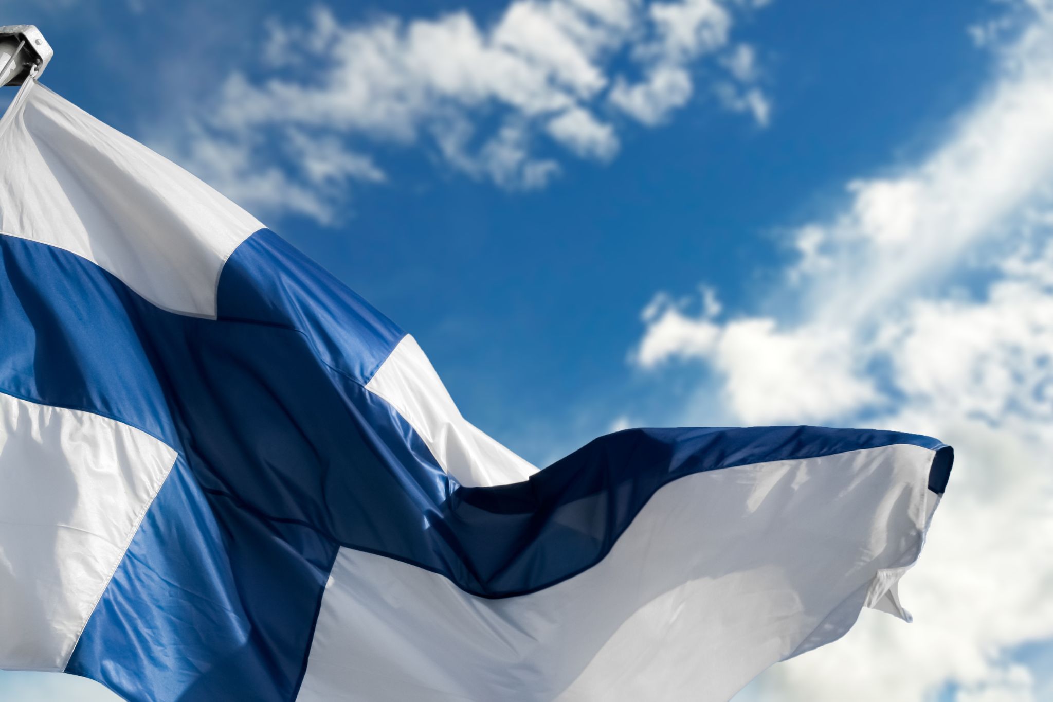 Kansallisen veteraanipäivän kenttähartaus Suomenlippu taivasta vasten.
