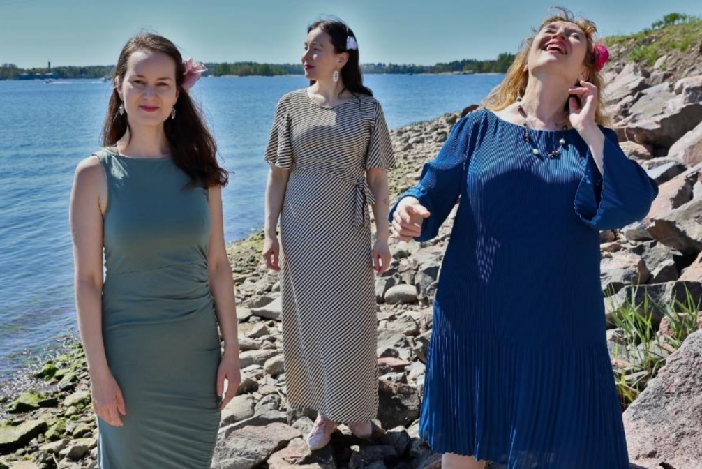 Kuvassa konsertin esiintyjät kallioisella merenrannalla.