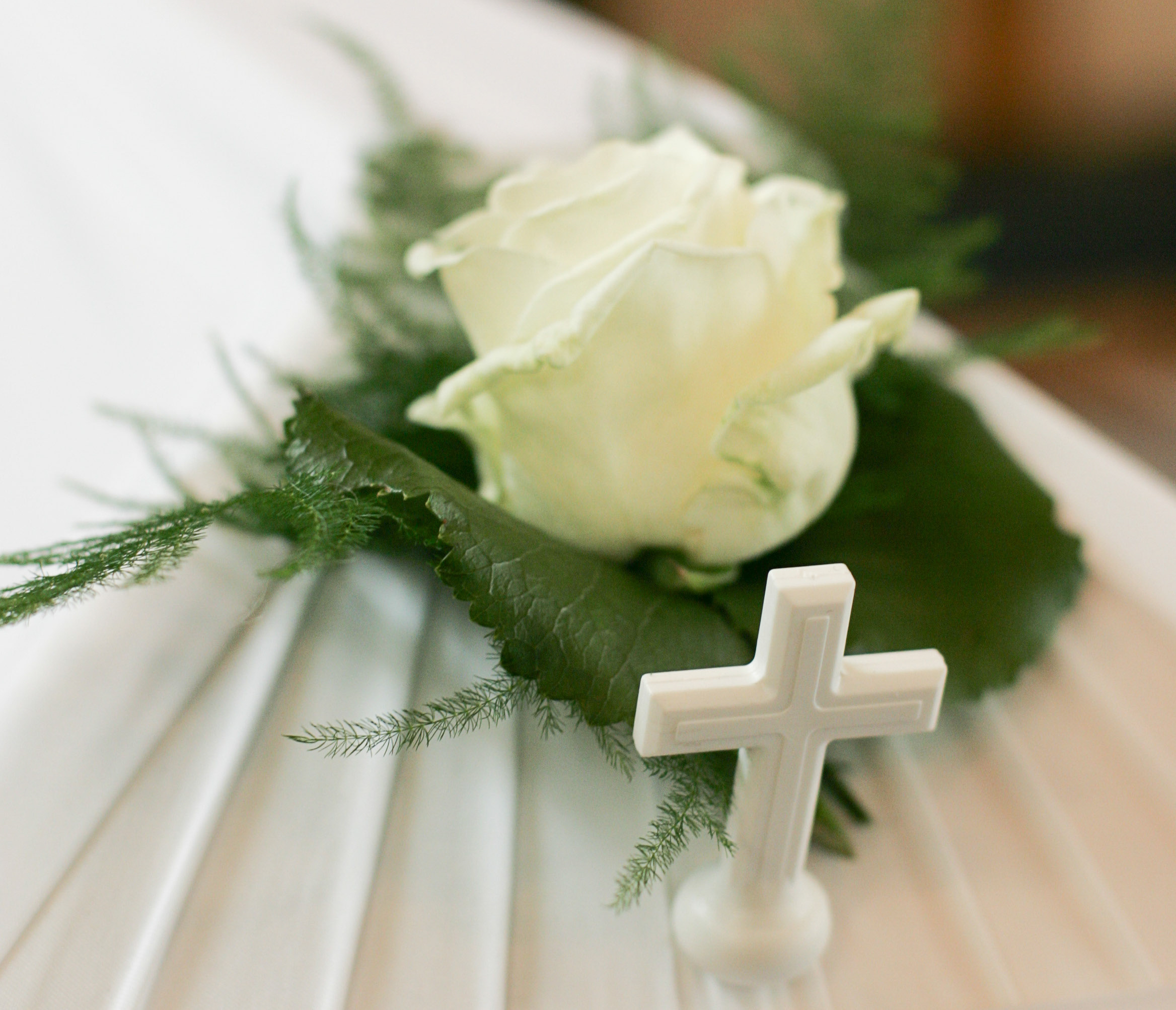 Siunaustilaisuus meneillään, valkoinen arkku, ruusu ja risti.