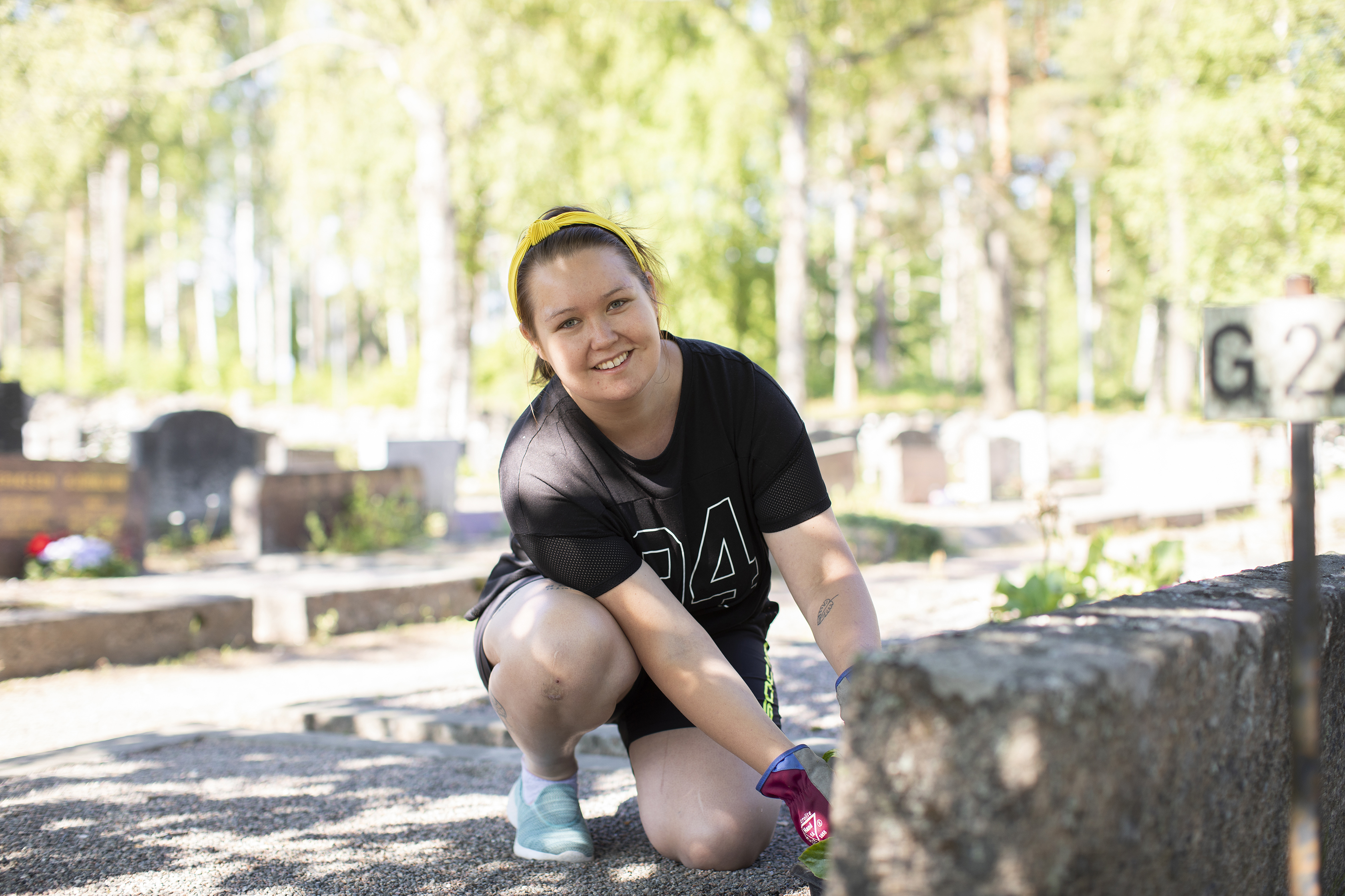 Iloinen kesätyöntekijä hautausmaalla.