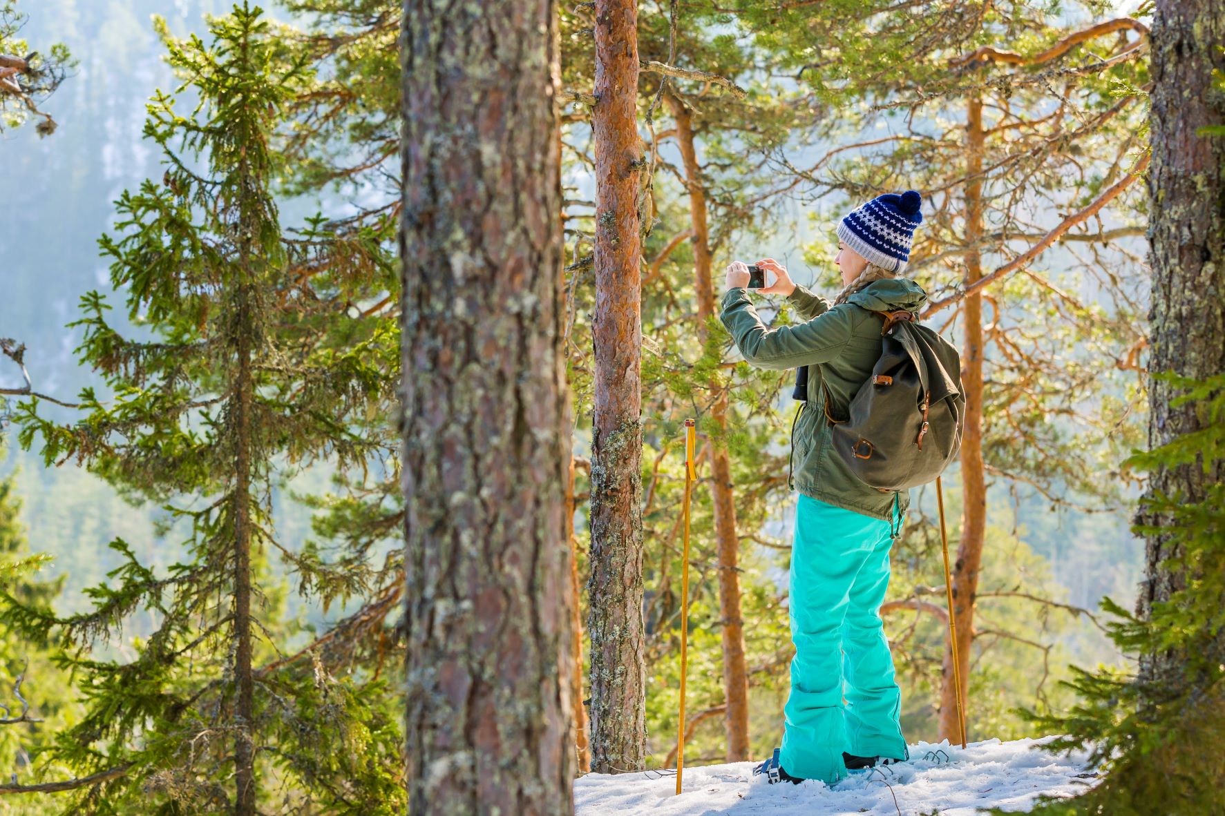 Nuori ottaa kuvia valoisassa metsässä.