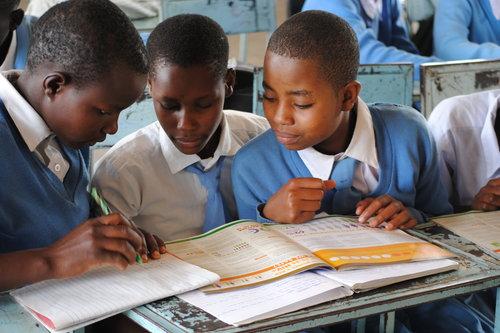 Kolme afrikkalaista poikaa tekemässä läksyjä